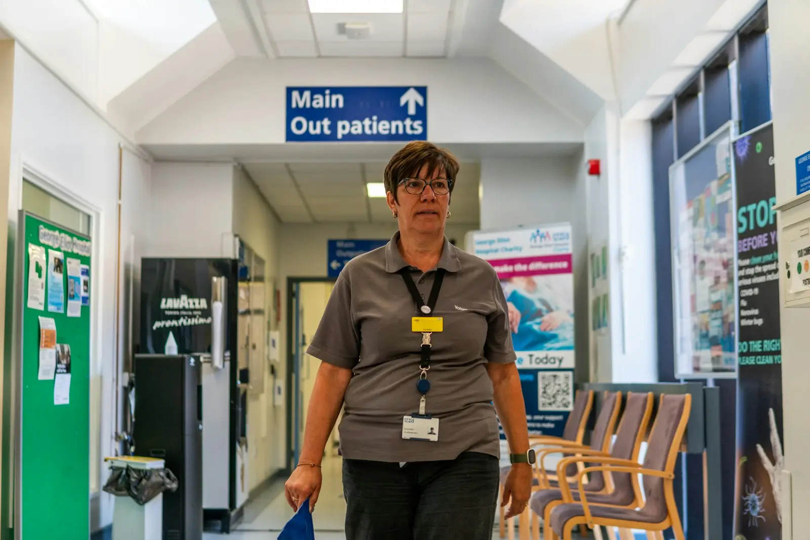 A member of staff walking through a hospital outpatients corridor